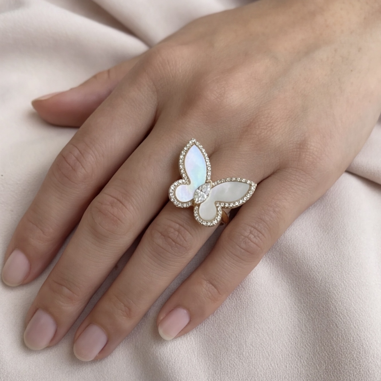 Mother of pearl butterfly ring worn on the hand against soft fabric - Pure Pearls