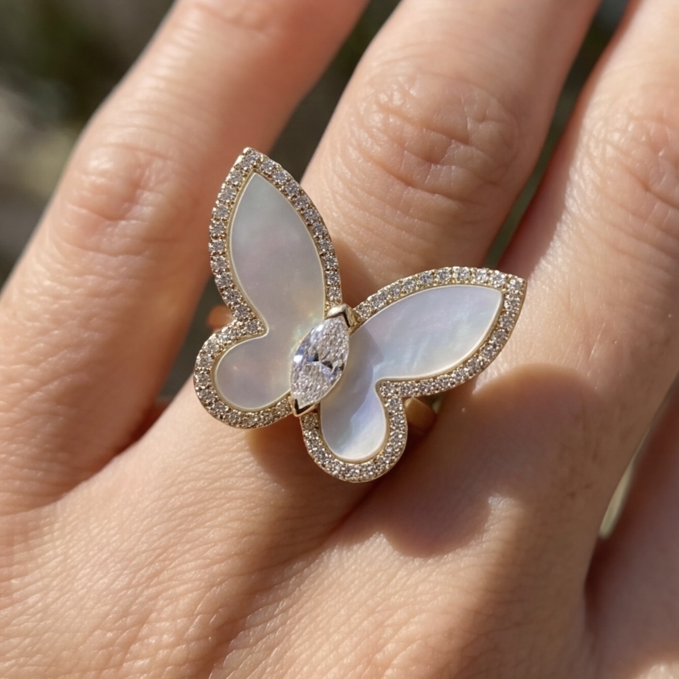 Mother of pearl butterfly ring worn on the finger in natural sunlight - Pure Pearls